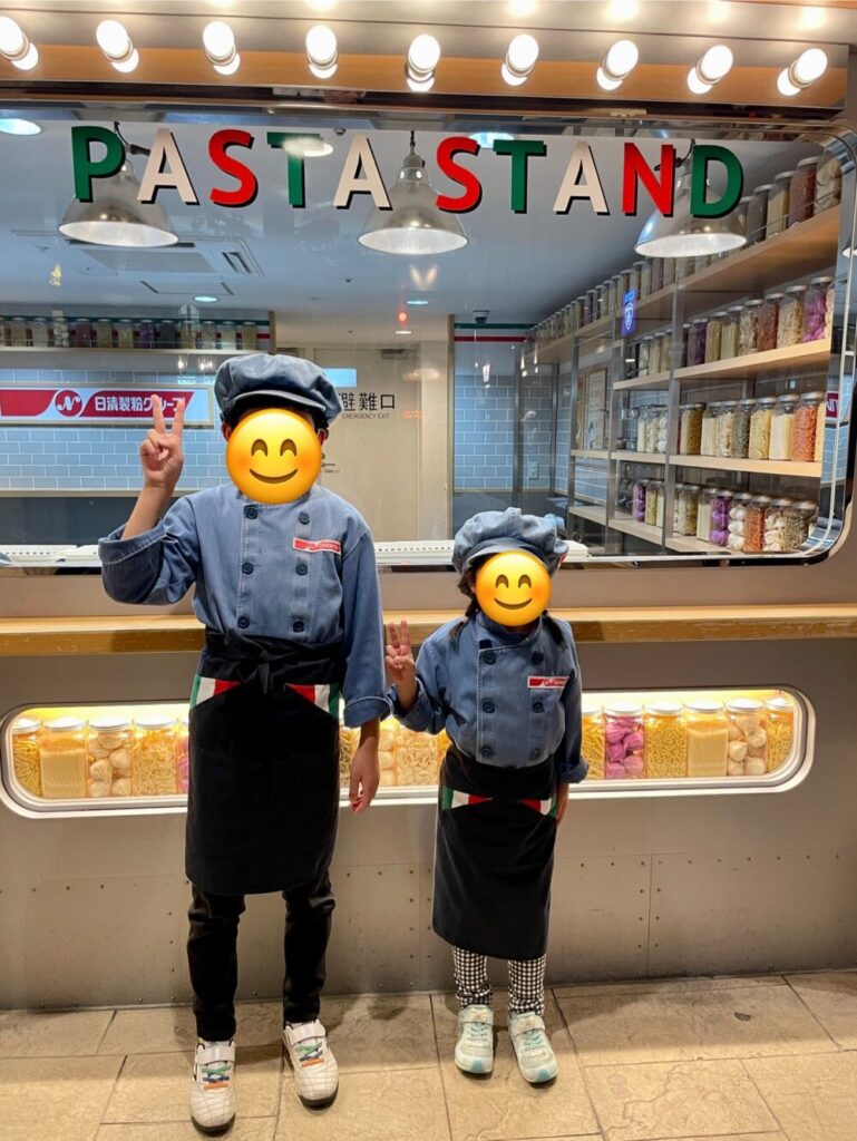 パスタスタンドの前でピースする兄妹